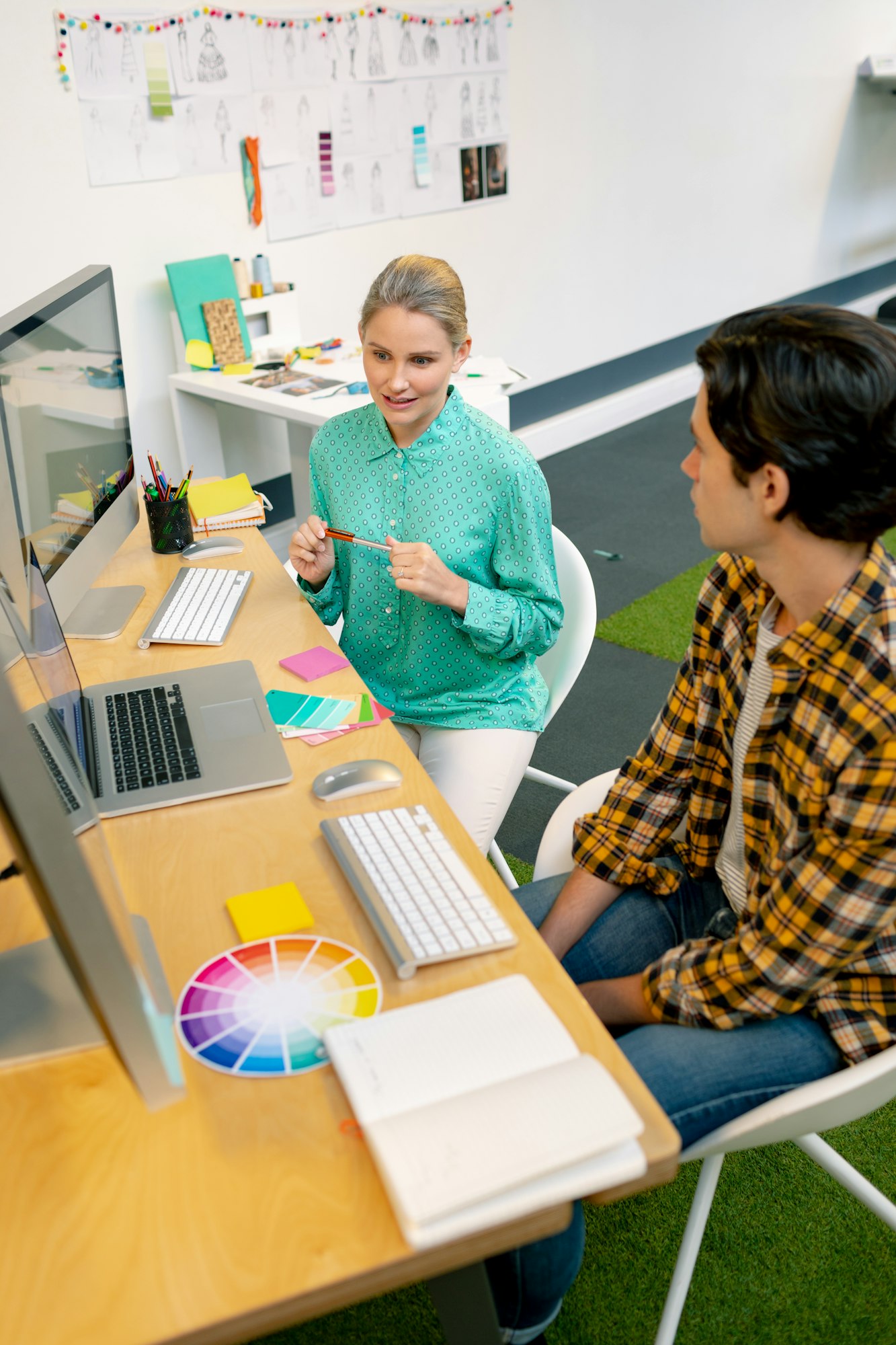 Caucasian male and female graphic designer discussing over computer at desk